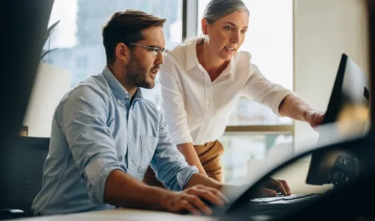 Man and woman coworkers looking at computer