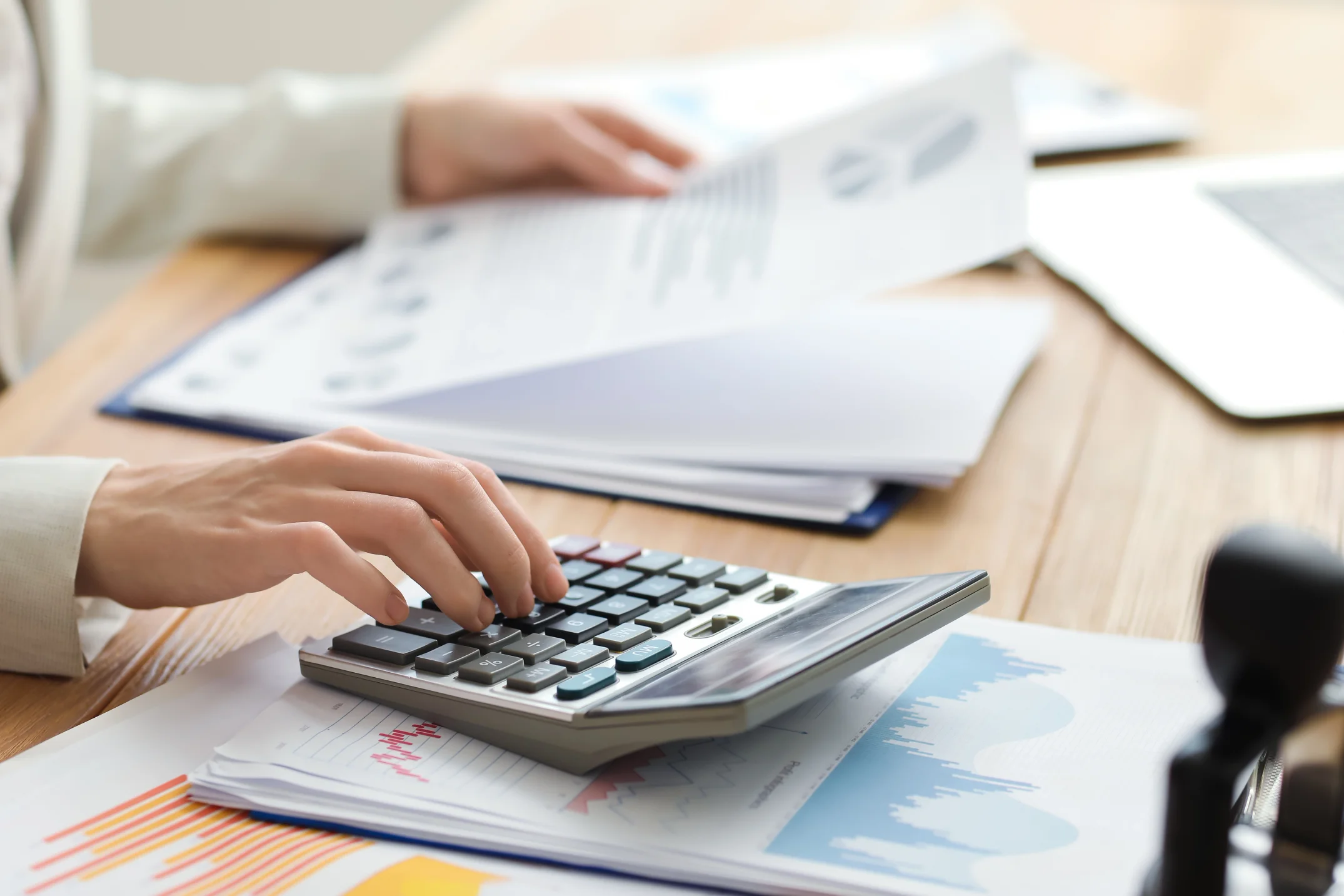 Female Accountant Working with Calculator and Documents at Table.
