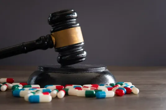 Legal gavel and assorted pills scattered on table