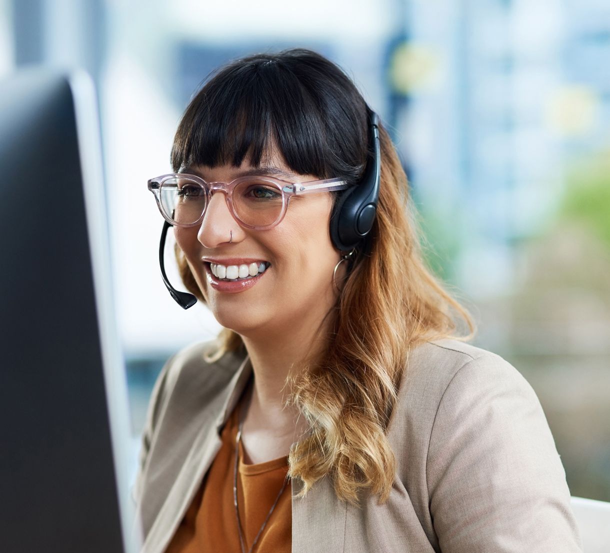 Woman with headset looking at computer screen