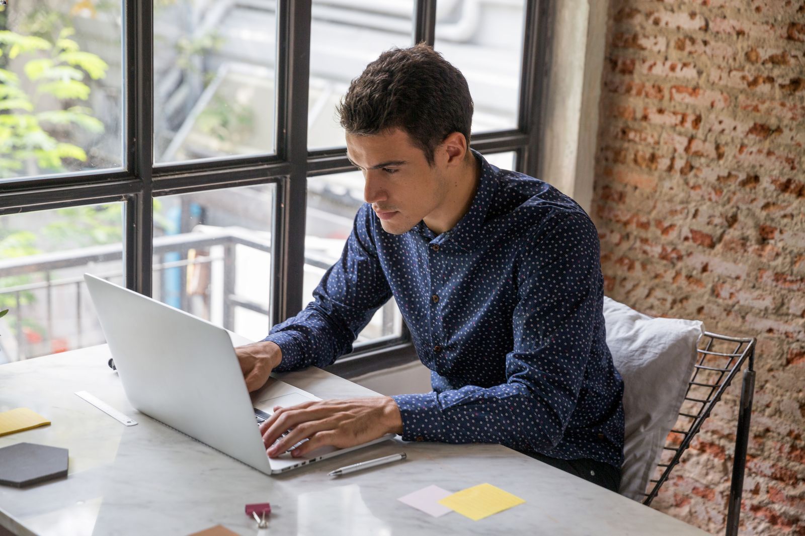 Man in navy shirt typing on laptop