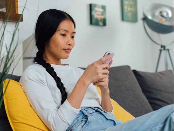 Woman sitting on couch looking at phone screen