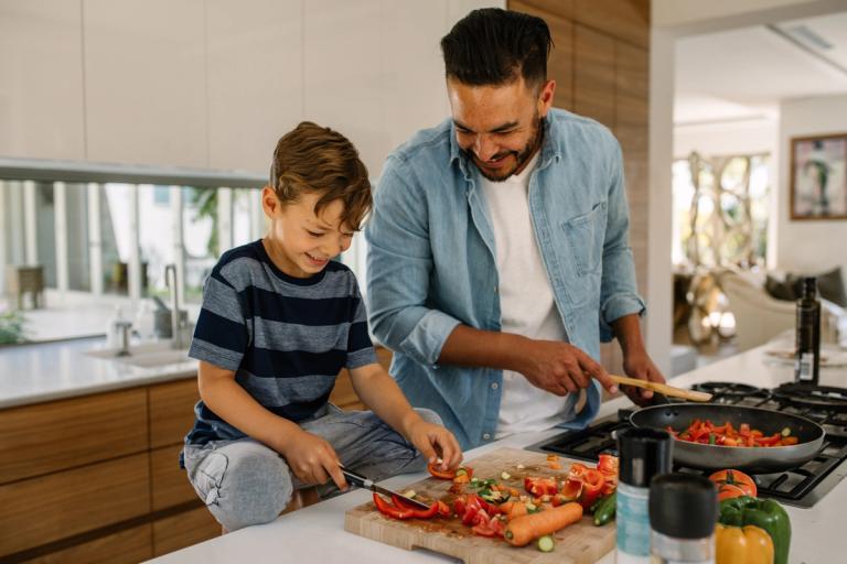 A father and son cook a healthy meal together.