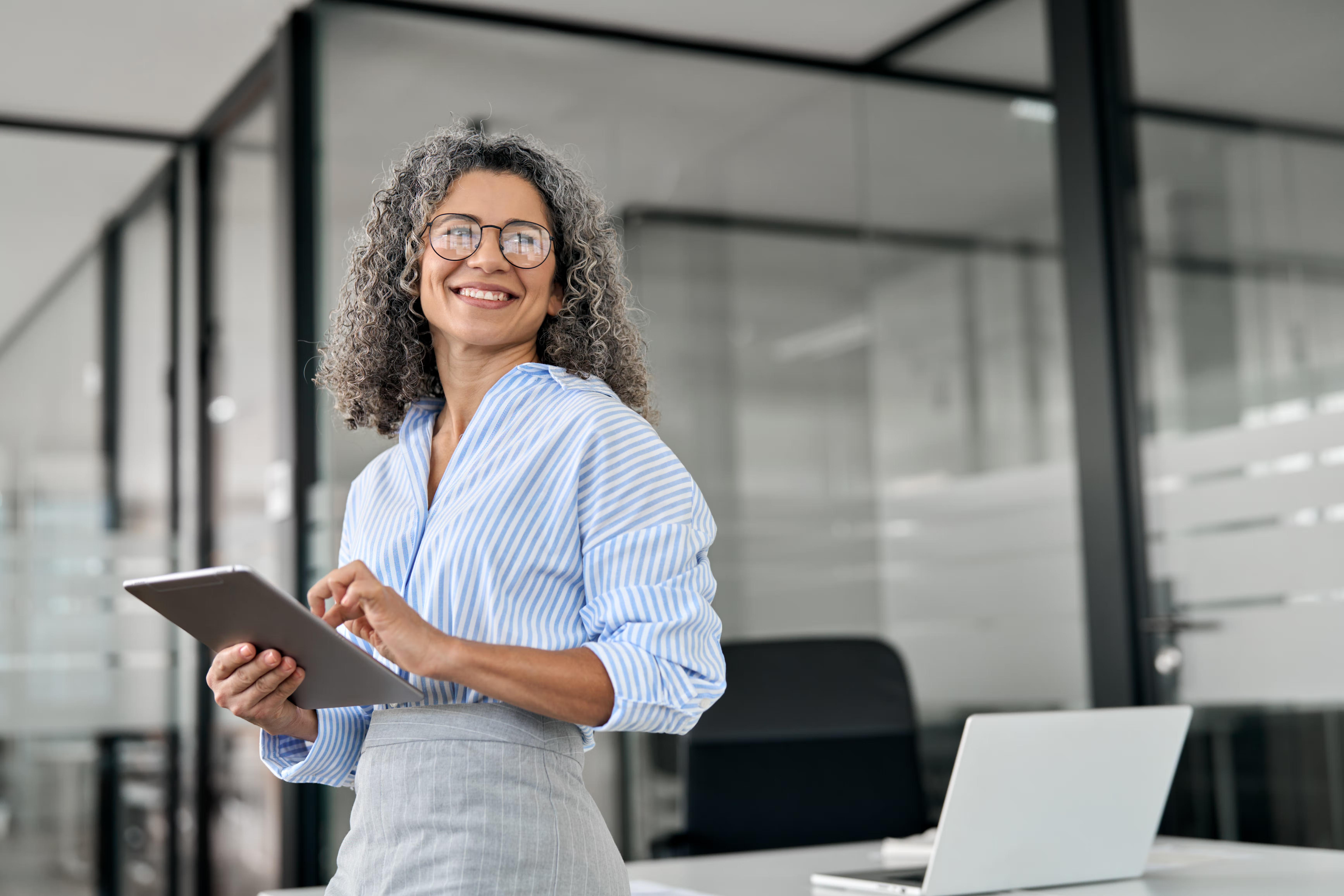 Smiling woman holding a tablet in an office.