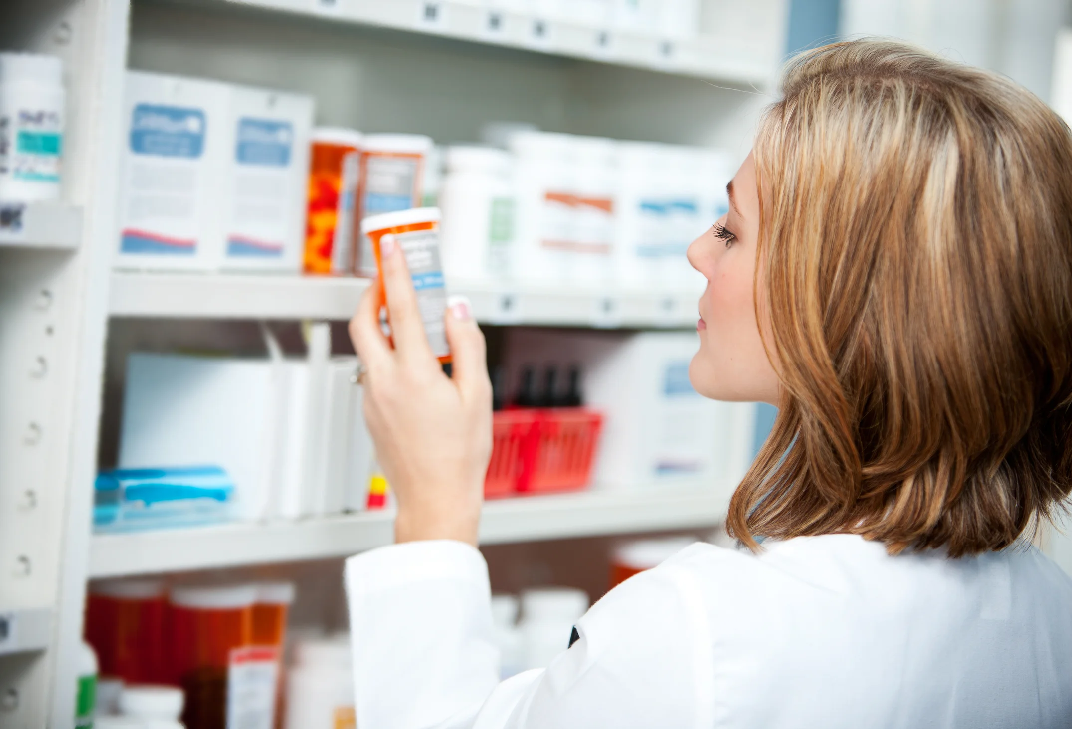 Pharmacist inspecting medication on shelf in pharmacy