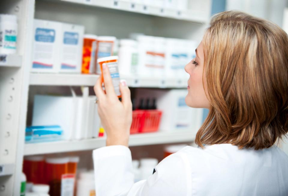 Pharmacist inspecting medication on shelf in pharmacy