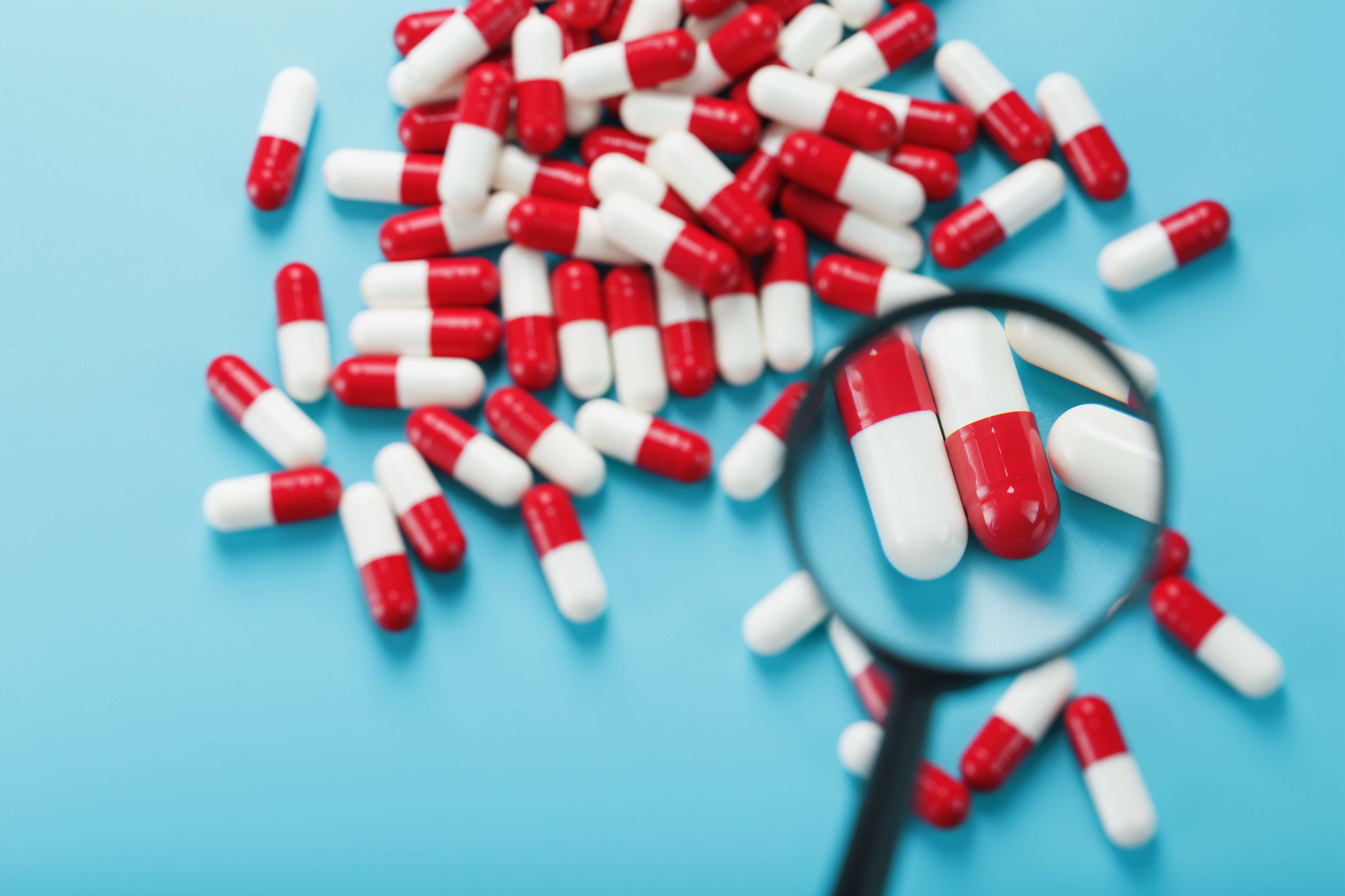 Magnifying glass enlarging pills on a blue background