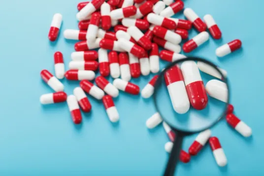 Magnifying glass enlarging pills on a blue background