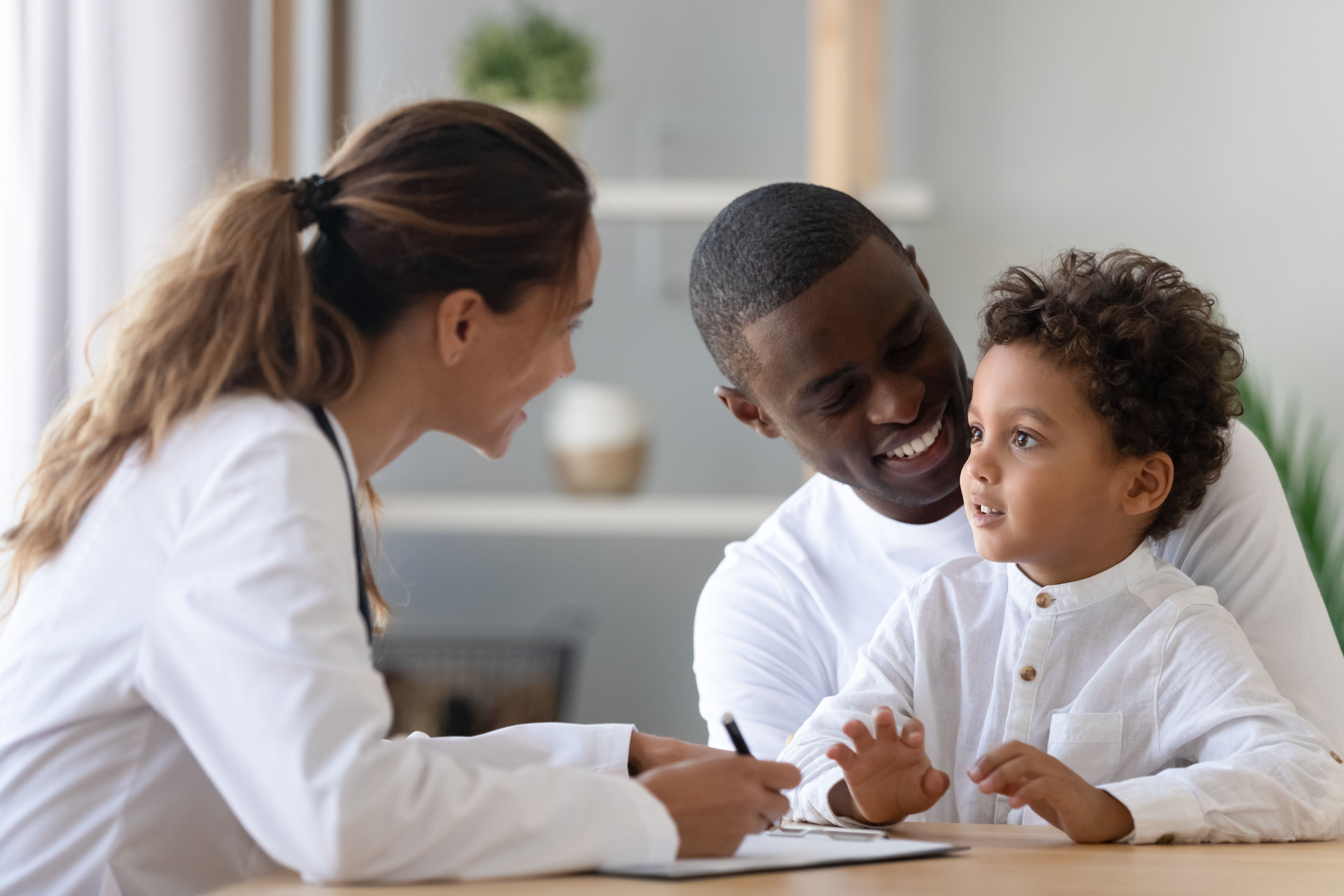 Father holding son as female doctor talk to them