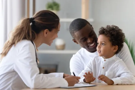 Father holding son as female doctor talk to them