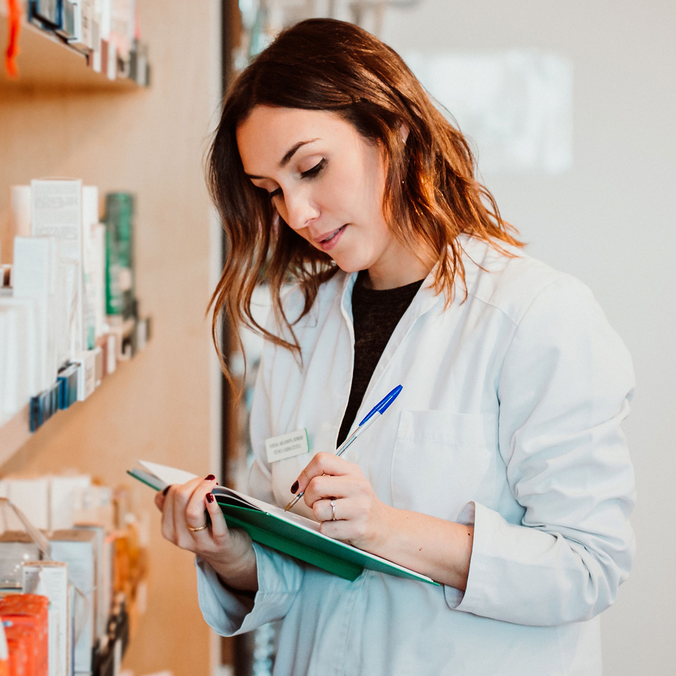 Pharmacist writing in notebook in pharmacy