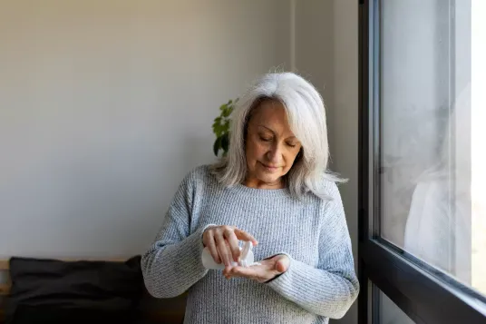 Woman dispensing pills into hand from pill bottle