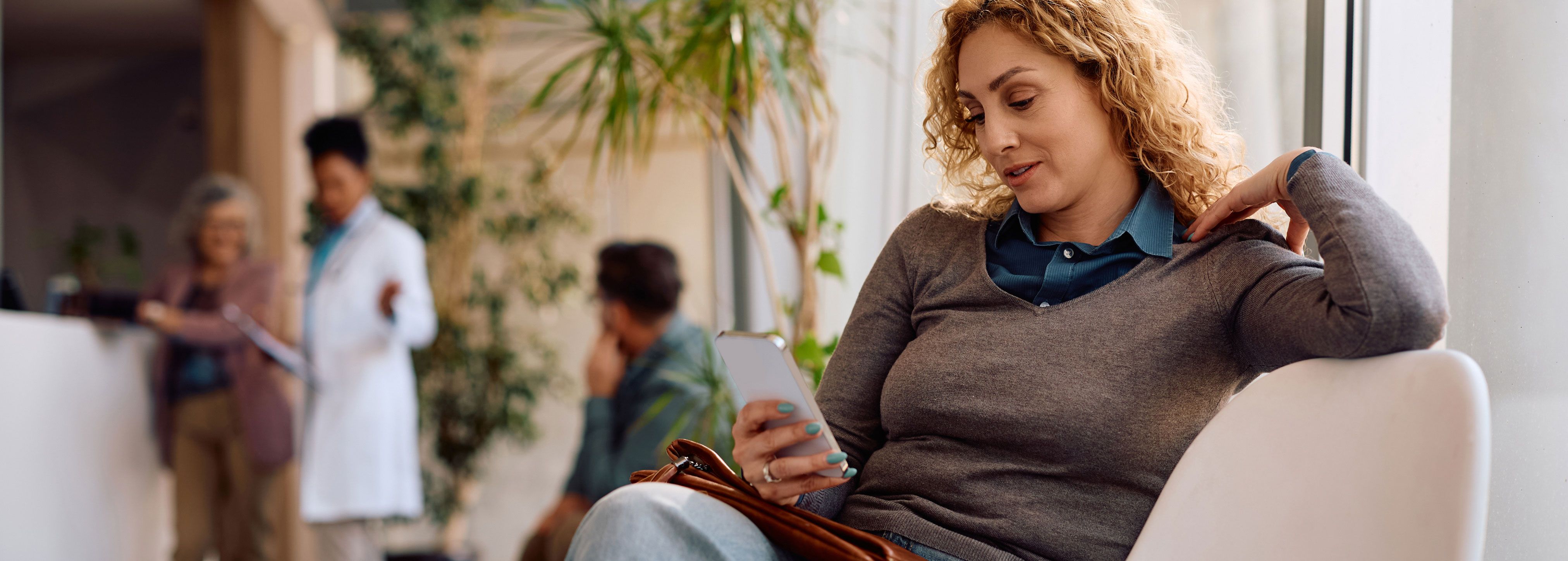 Woman looking at phone in a medical office waiting room
