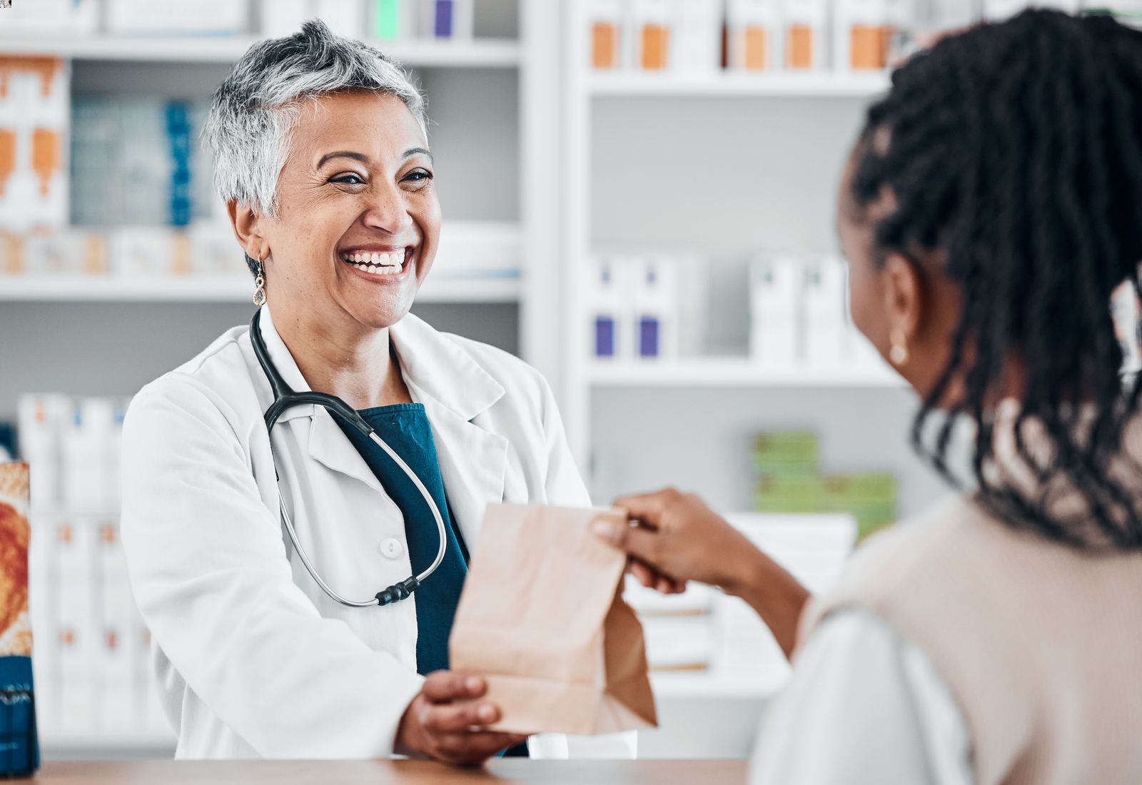 Smiling pharmacist landing patient a prescription at the pharmacy
