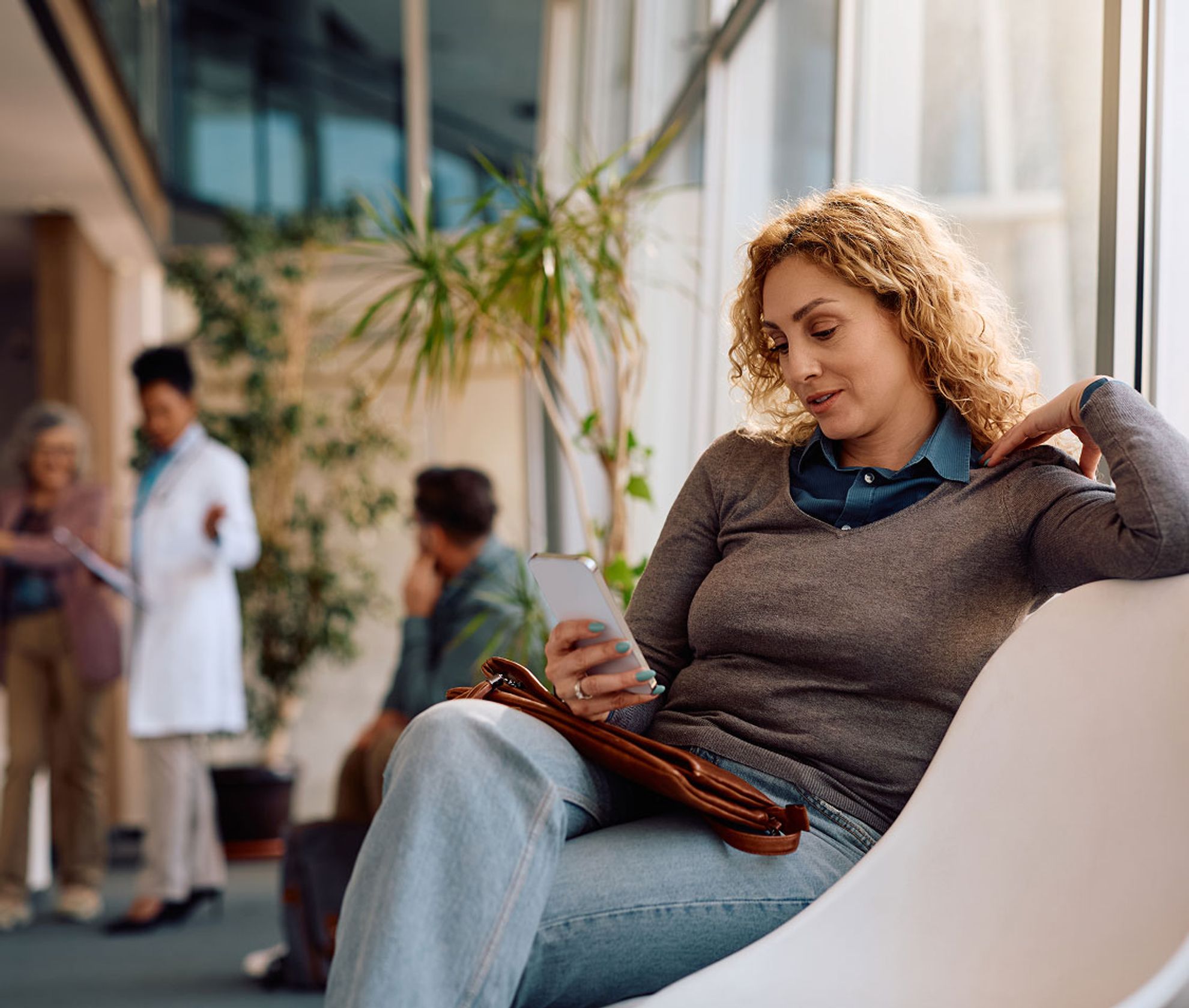 Woman looking at phone in a medical office waiting room