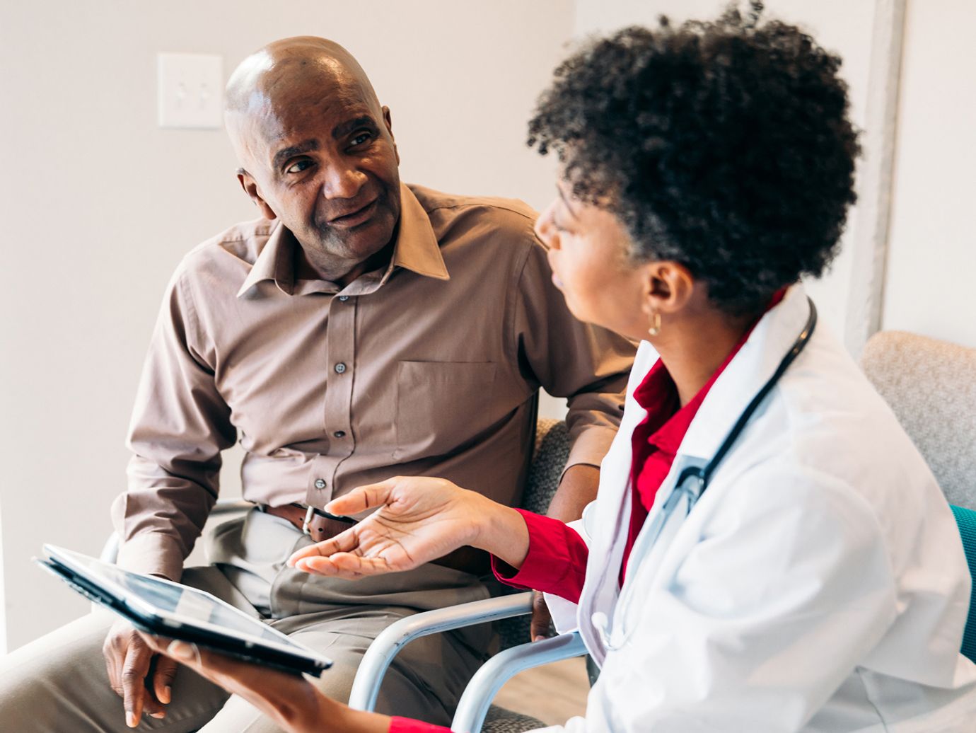 older male speaking with physician in doctors office