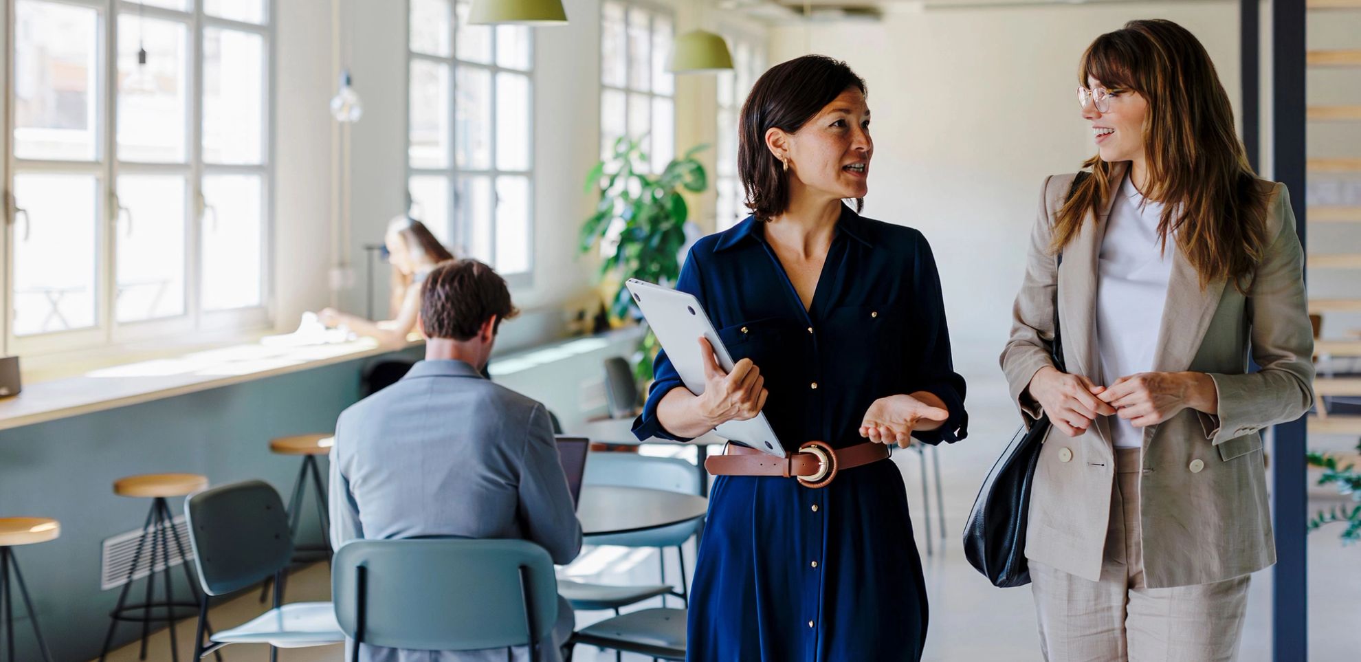 Two coworkers chatting and walking in office setting