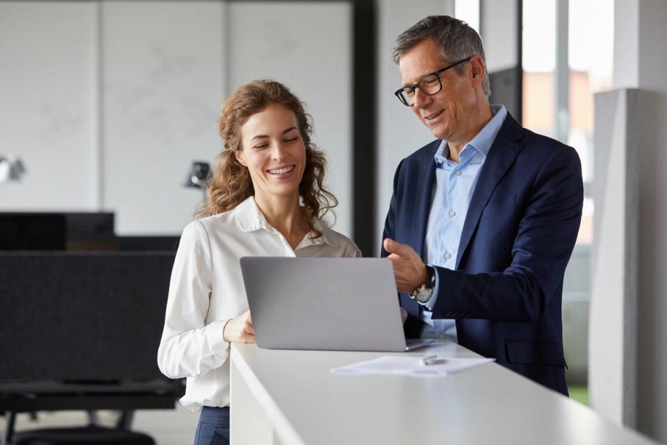 Man and woman coworkers standing and looking at computer screen