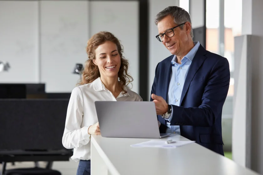 Man and woman coworkers standing and looking at computer screen