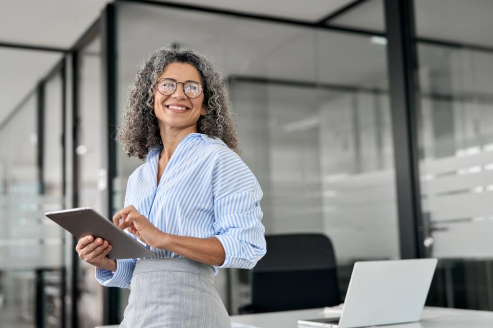 Smiling woman holding a tablet in an office.