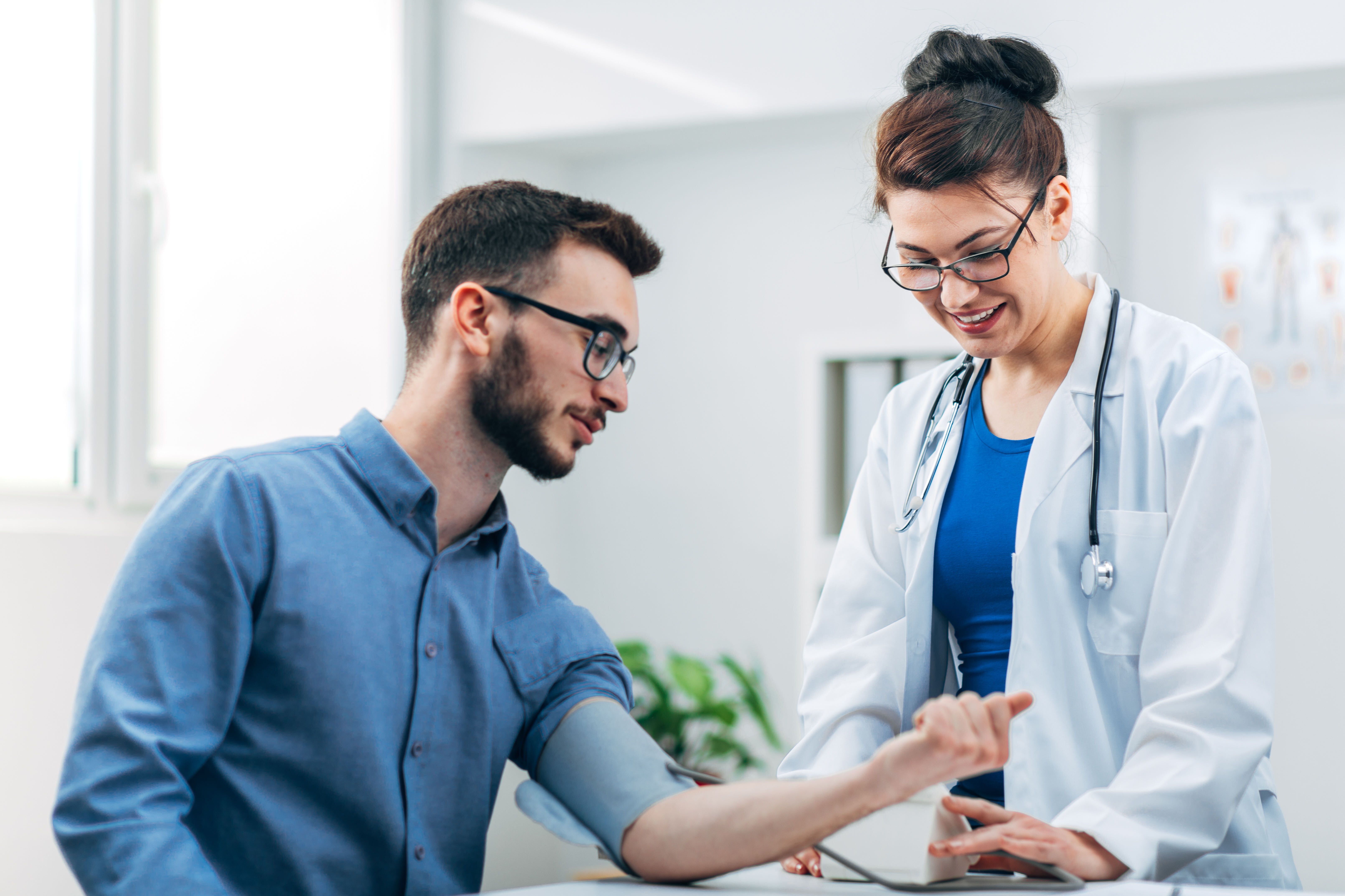 Man getting his blood pressure taken by female doctor