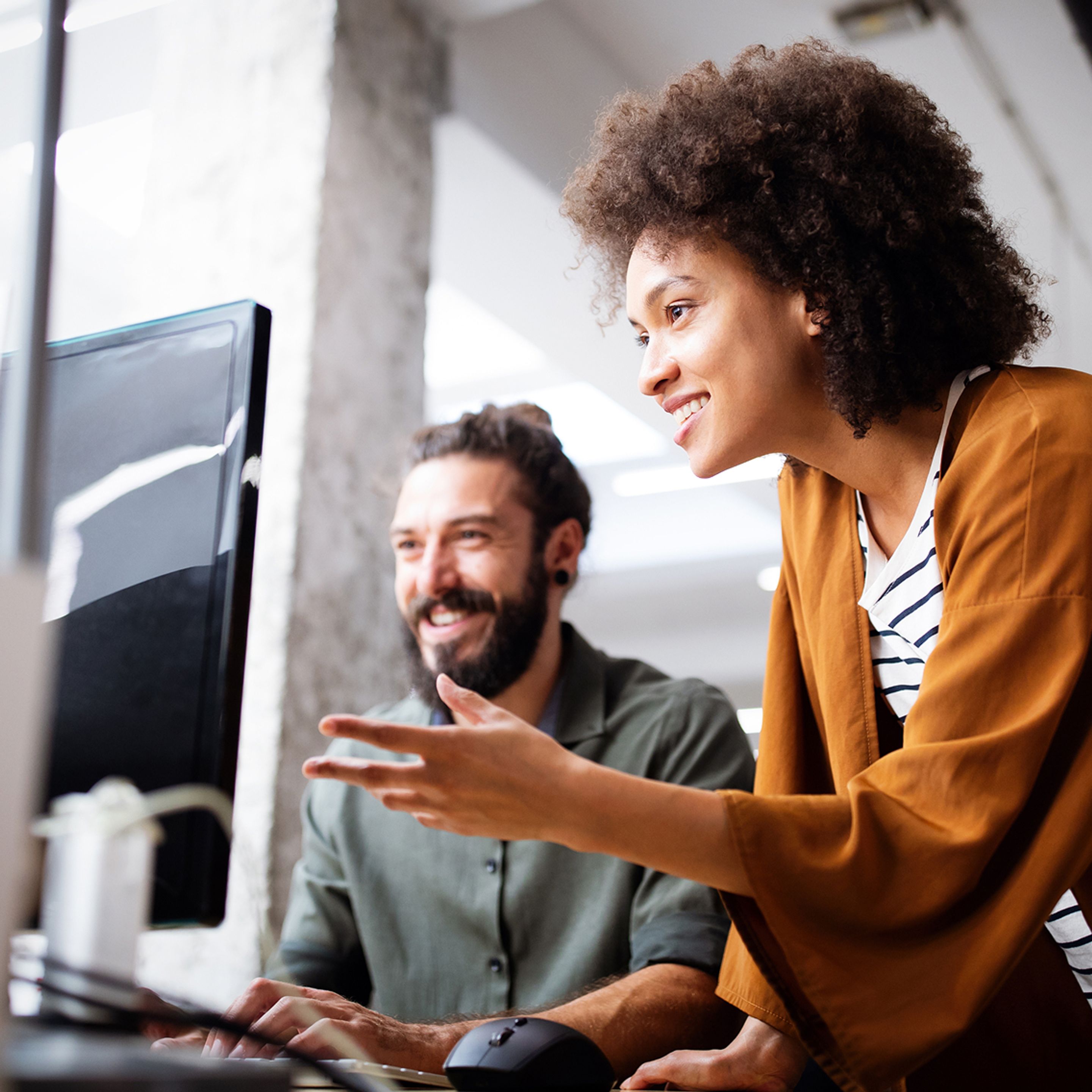 Two coworkers looking at computer screen smiling