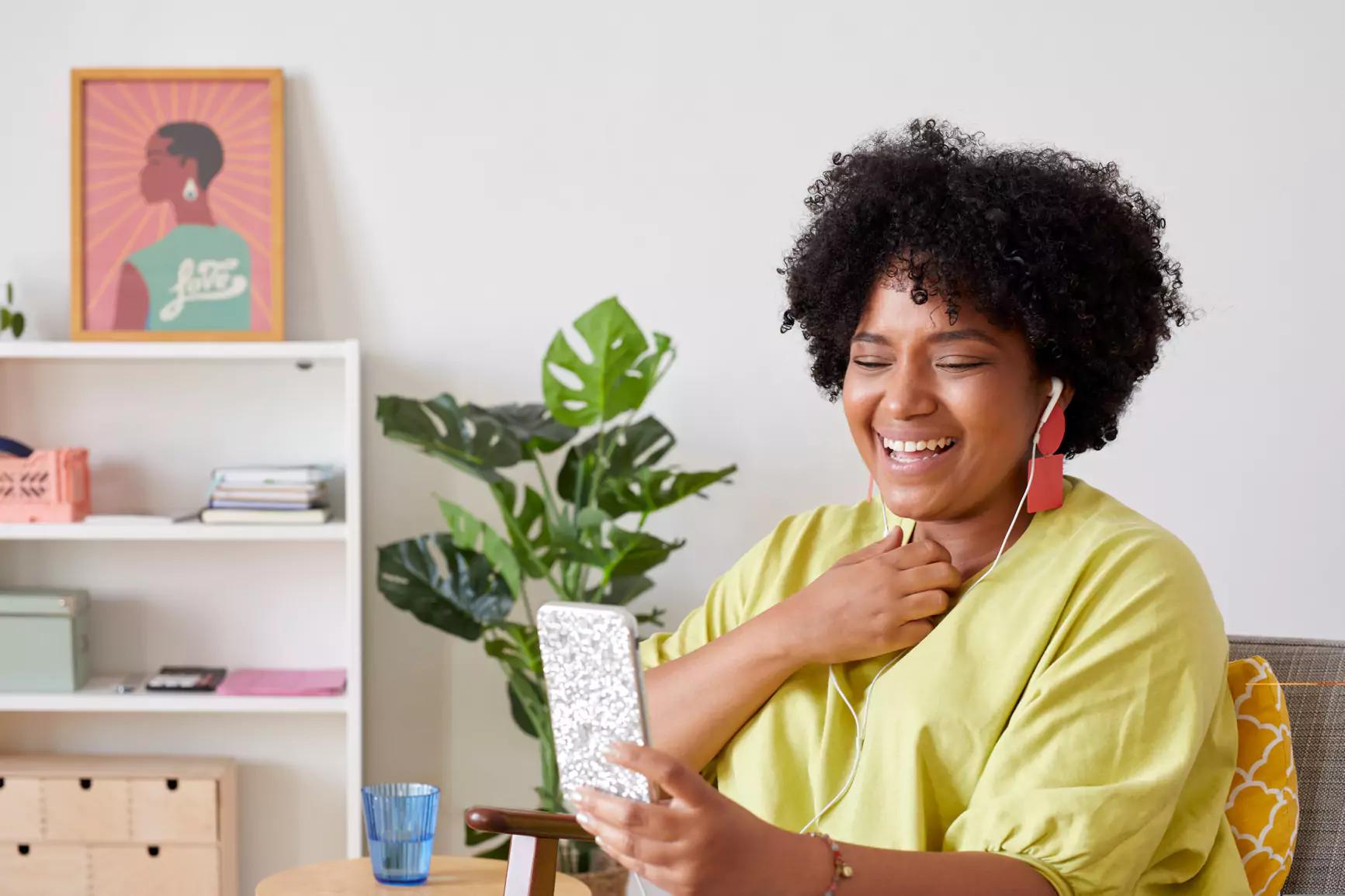 Woman in yellow shirt smiling and looking at phone