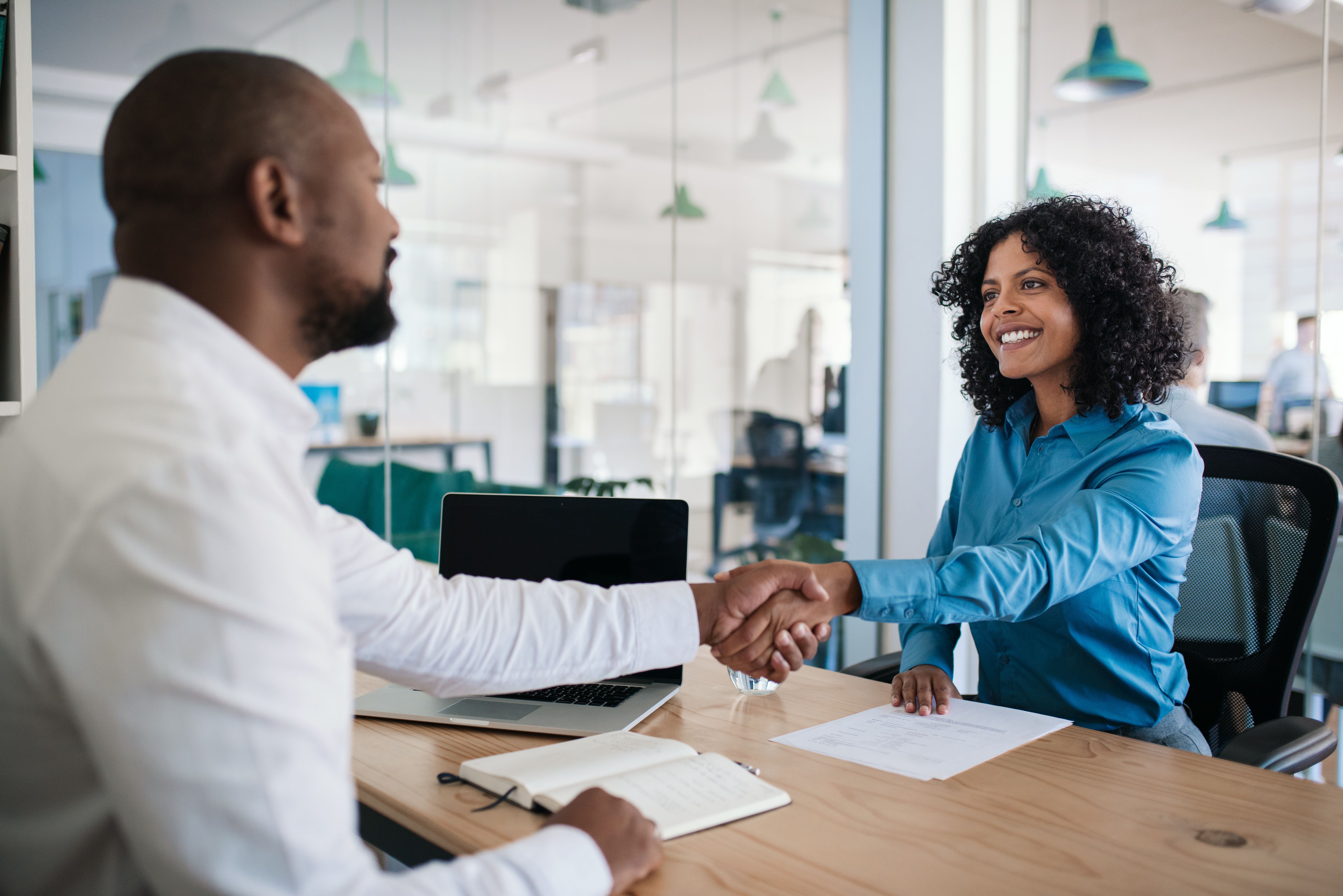 Man and woman shaking hands over desk