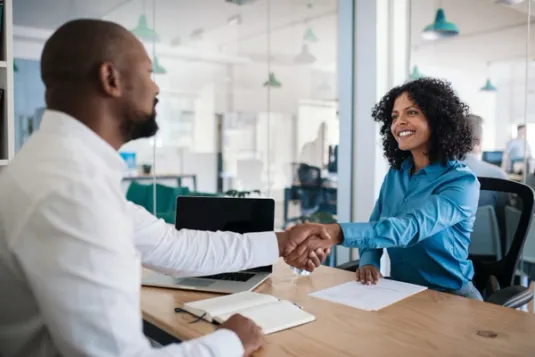 Man and woman shaking hands over desk