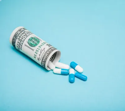 Rolled up money in the shape of a pill bottle with pills spilling out