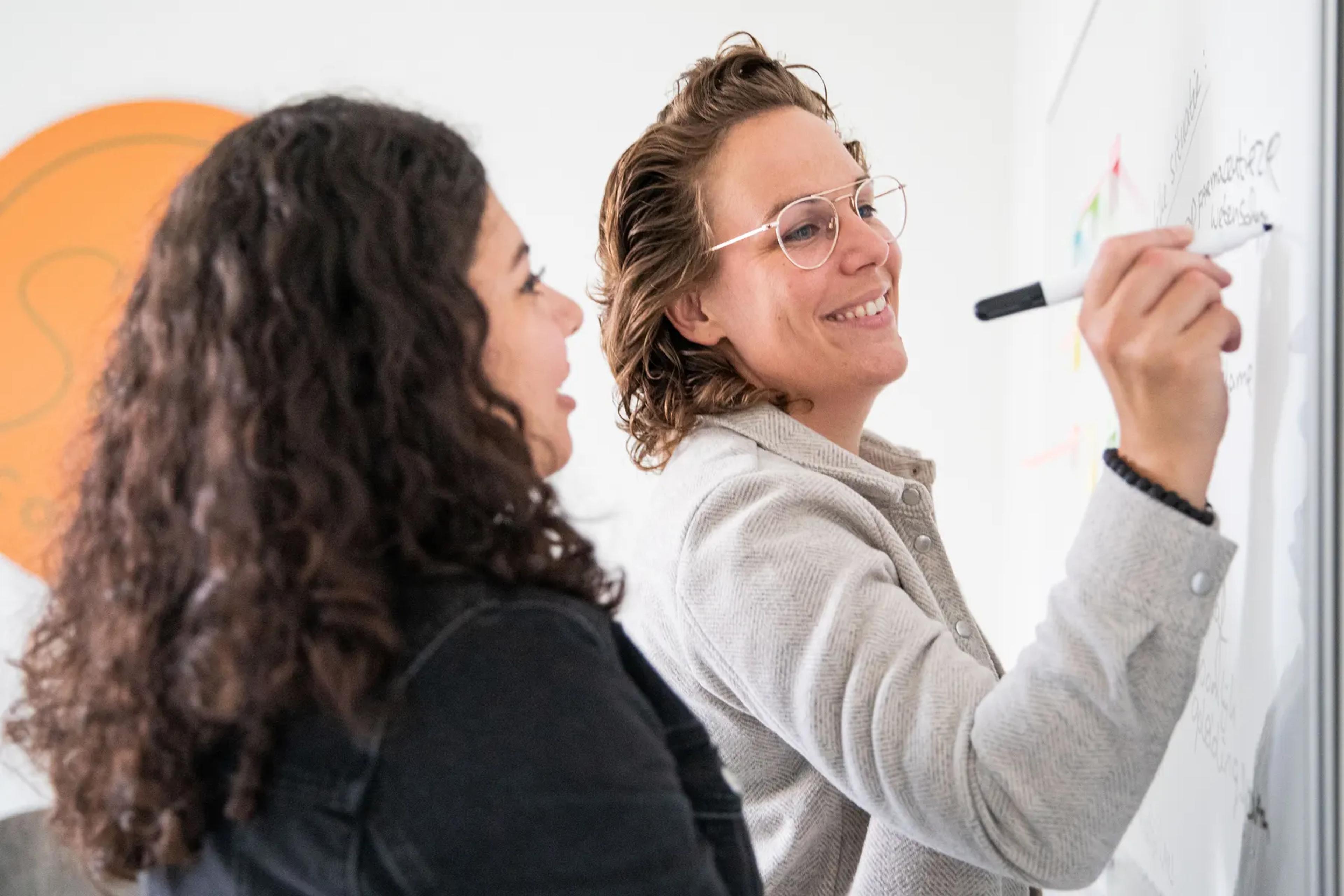 Samantha schrijft samen met een cliënt op het whiteboard