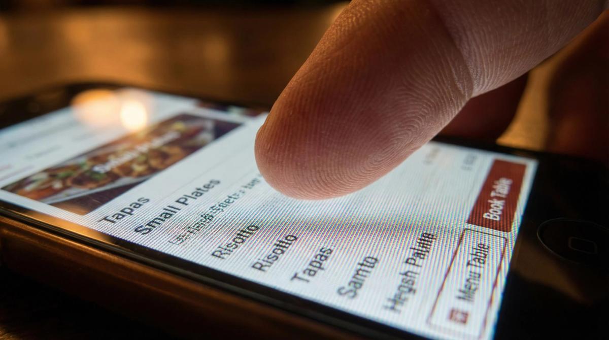 Close-up van een vinger die probeert te navigeren op een mobiele website met te kleine knoppen en tekst.