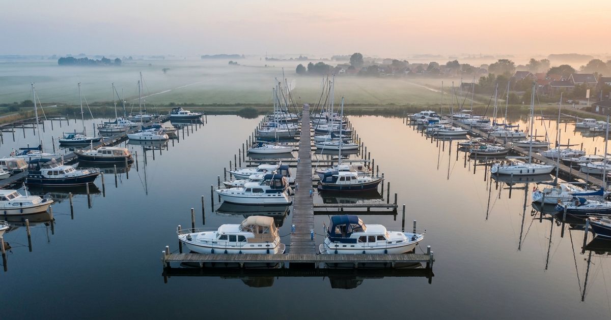 Aerial view of a marina with motor boats and sailing yachts in soft morning light
