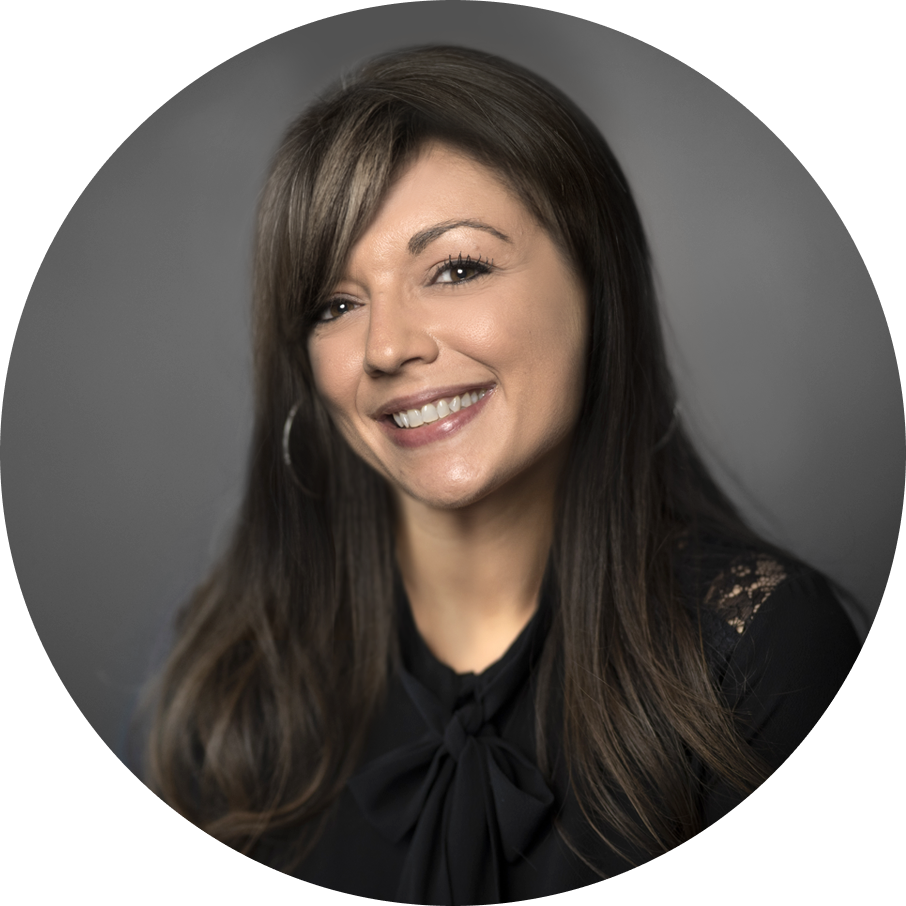 Smiling woman with long brown hair wearing a black top against a grey background.