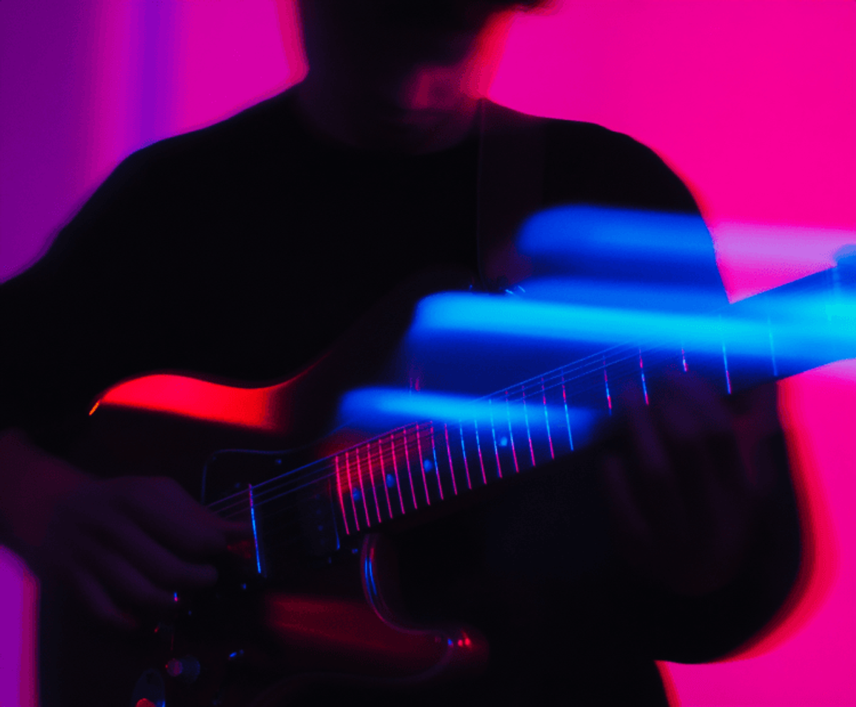 Guitarist playing under colorful neon lights