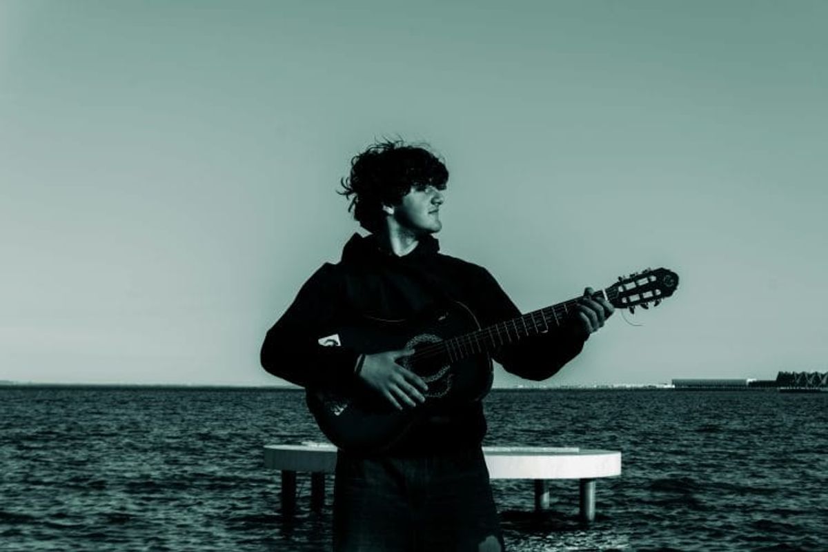 Person playing guitar by the sea