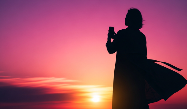 Silhouetted creator with smartphone against vivid sunset representing influencer marketing
