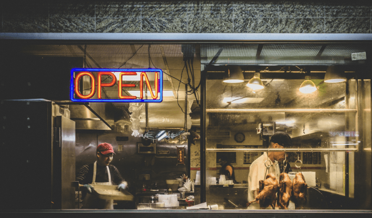 Restaurant kitchen with open sign and chefs inside.