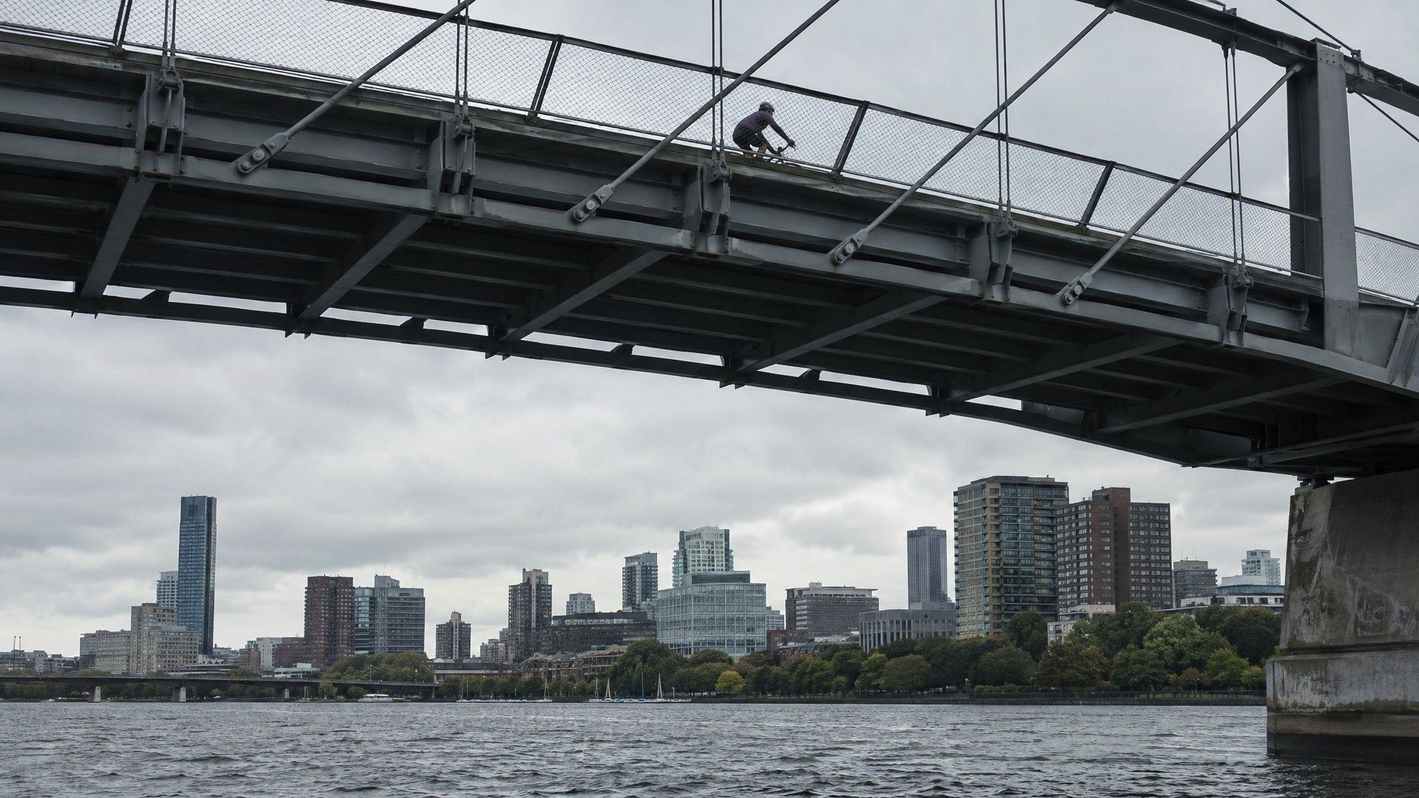 Steel footbridge over a river seen from below with a cyclist