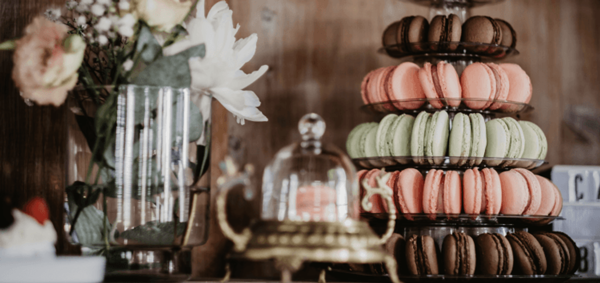 Colorful macarons on a tiered stand with flowers.