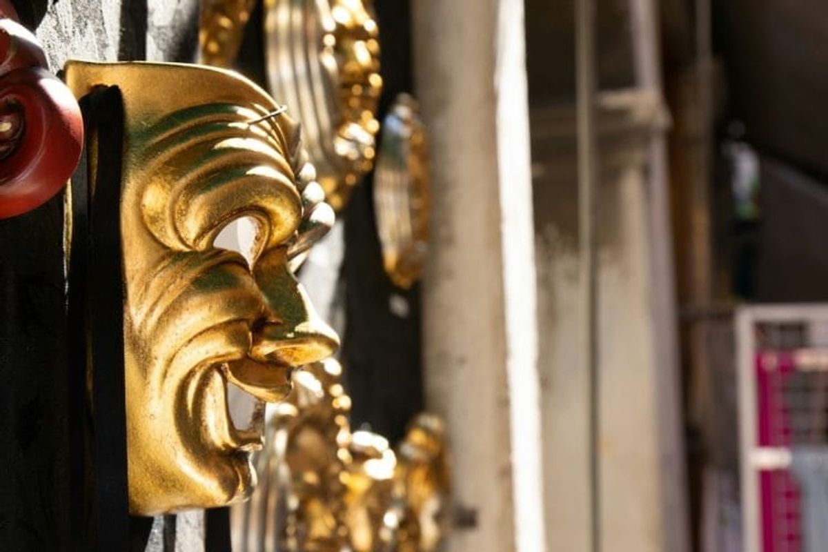 Golden theater mask on display outdoors.