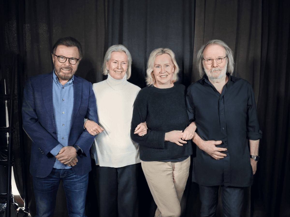 Four people standing together, smiling.