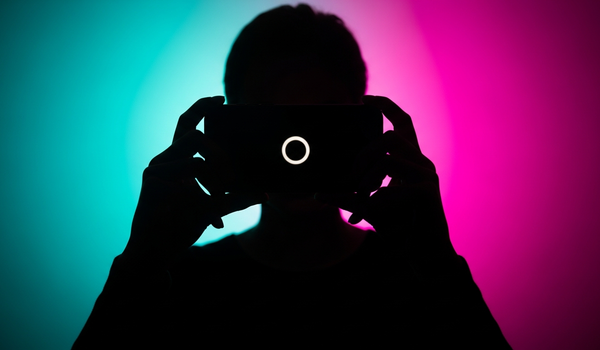 Silhouetted creator with vertical phone in vivid neon lighting representing TikTok marketing