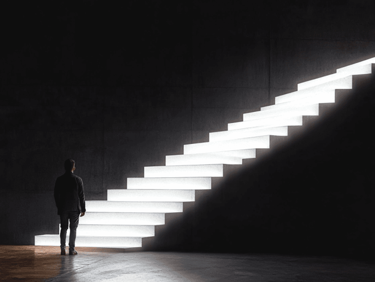 Man standing near illuminated staircase in dark room.