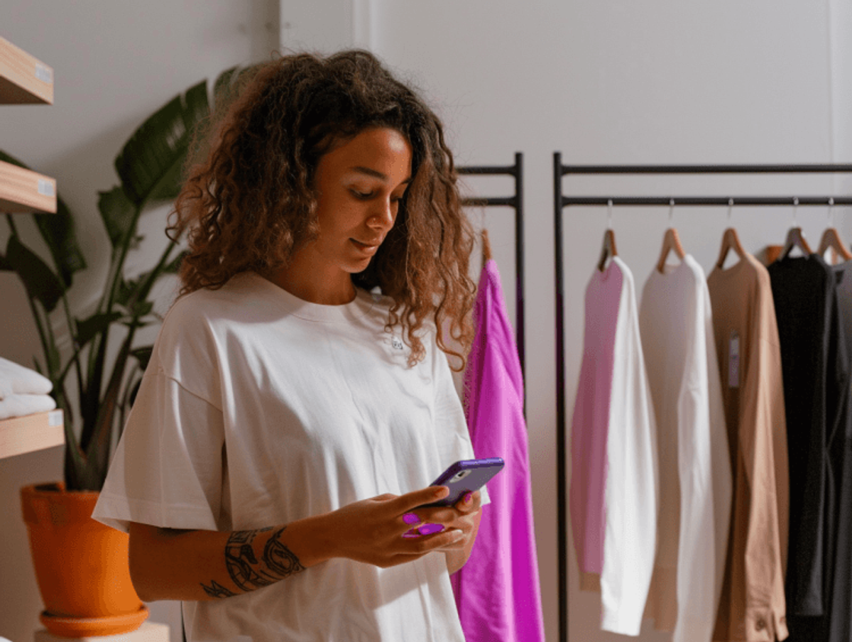 Woman using phone in a clothing store.