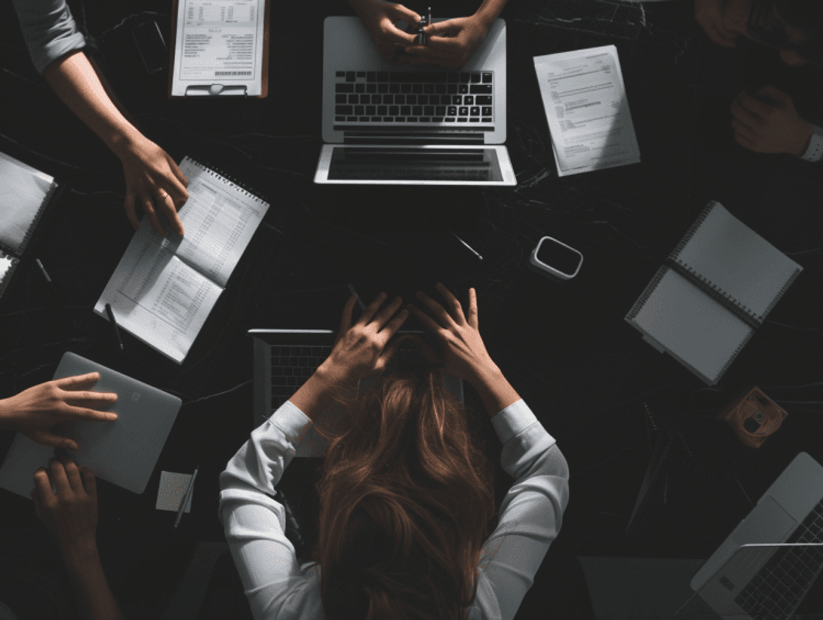 Team collaborating over laptops and documents at table.