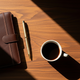 Artistic overhead shot of premium dark walnut desk with leather planner, gold pen, and espresso