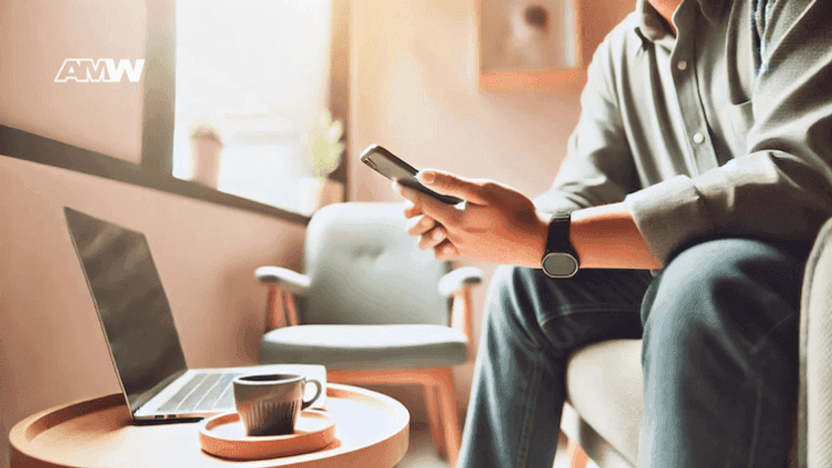 Man using phone, laptop and coffee on table.