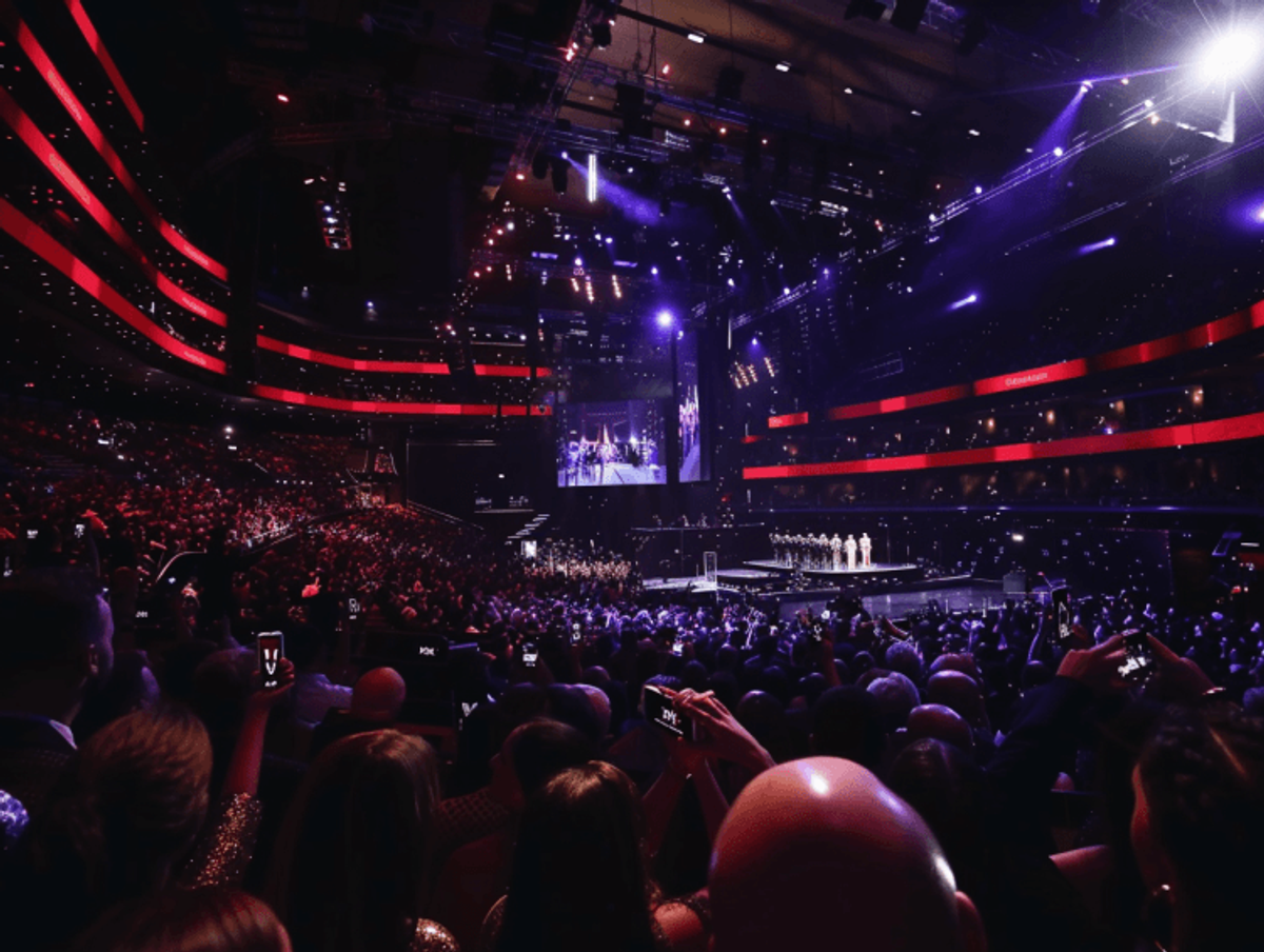 Crowd at large indoor concert event, vibrant lighting.