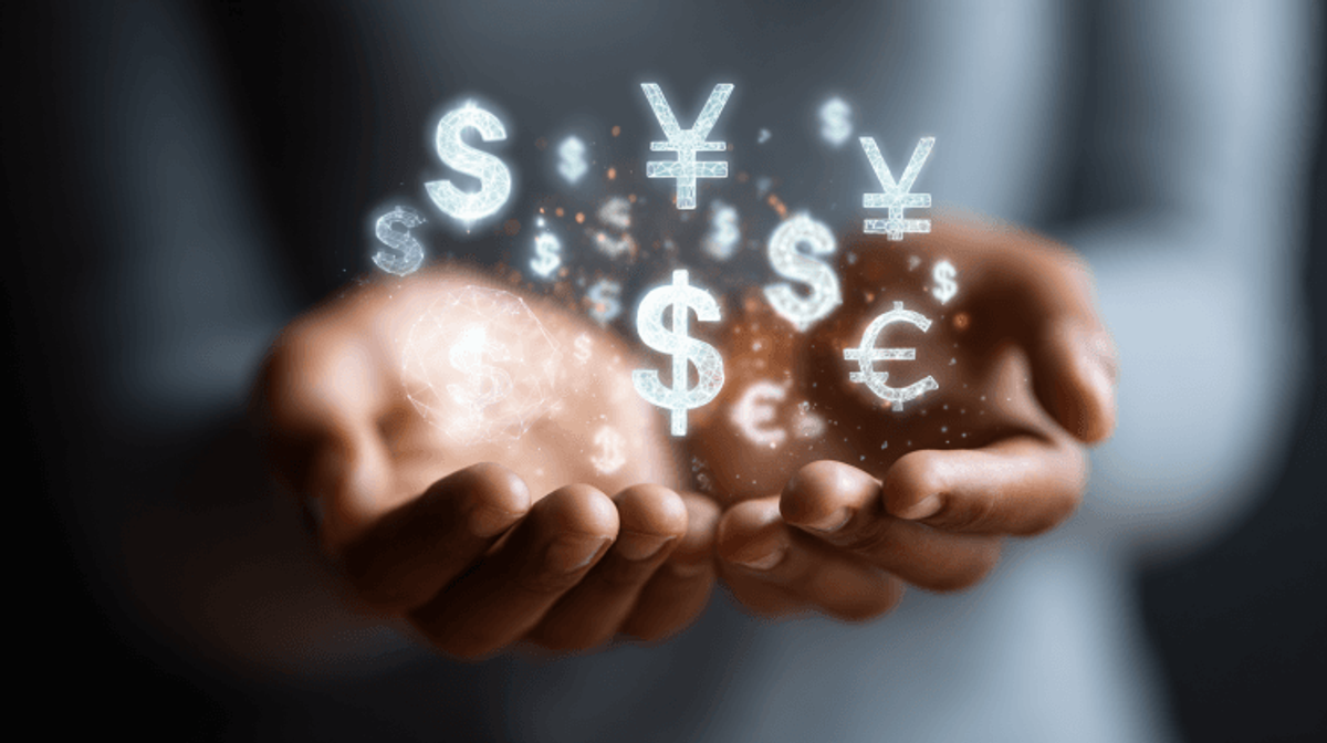 Hands holding floating global currency symbols.